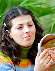A girl looking at a round mirror. Photo credit: Oleg Prikhodko