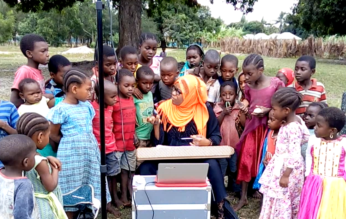 A team member in Zanzibar explains the mapping process to local children in a project community. A team member in Zanzibar explains the mapping process to local children in a project community.