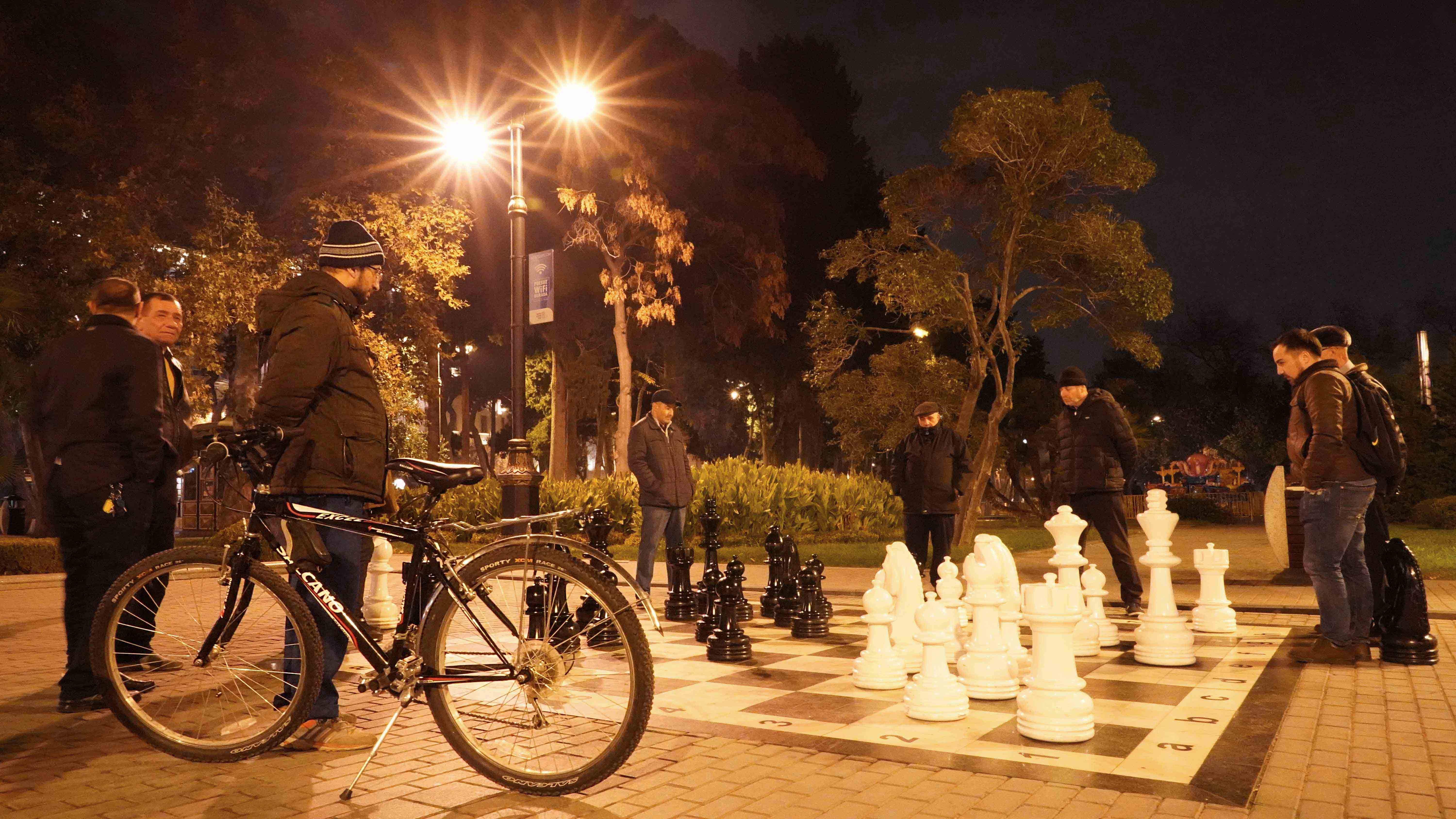 Fuad observing citizens playing chess in the central park of Baku