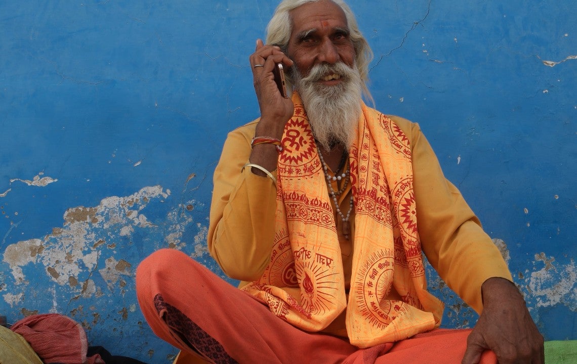 An old Indian monk talking on the phone