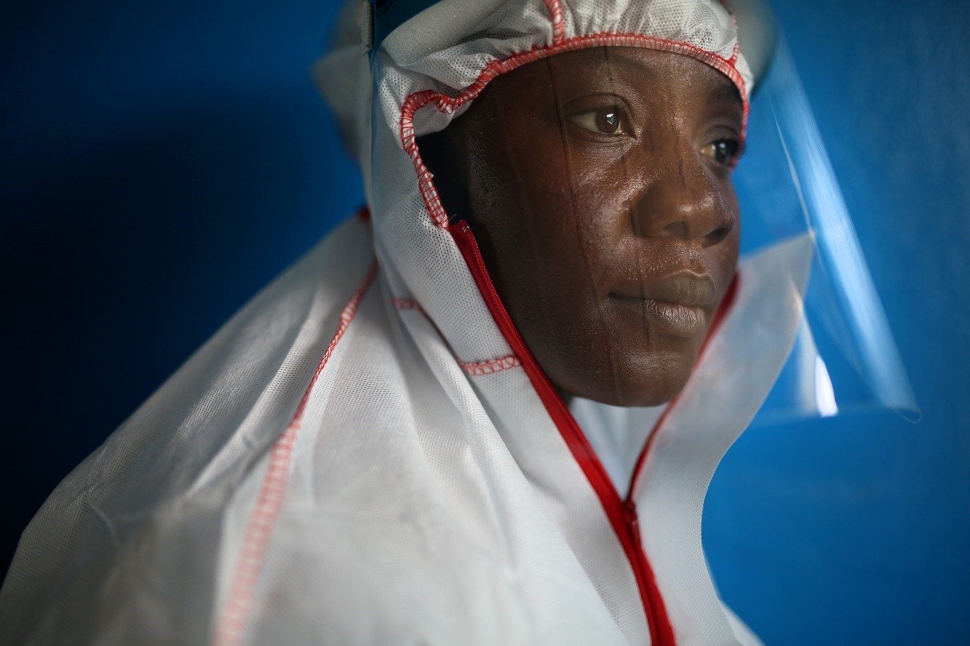 A healthcare worker wearing a protective face shield and a medical protective suit