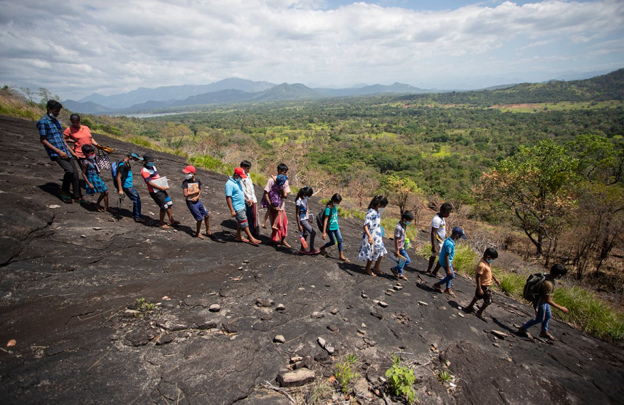 Sri Lankan children walk down a mountain after attending their online lessons in a forest reserve in Bohitiyawa village in Meegahakiwula.