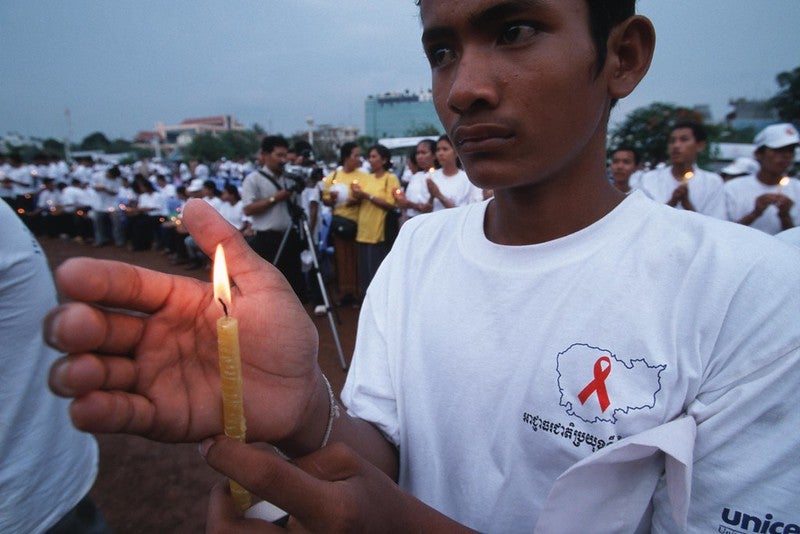 A campaigner holds a candle for people who have died of AIDS at a rally
