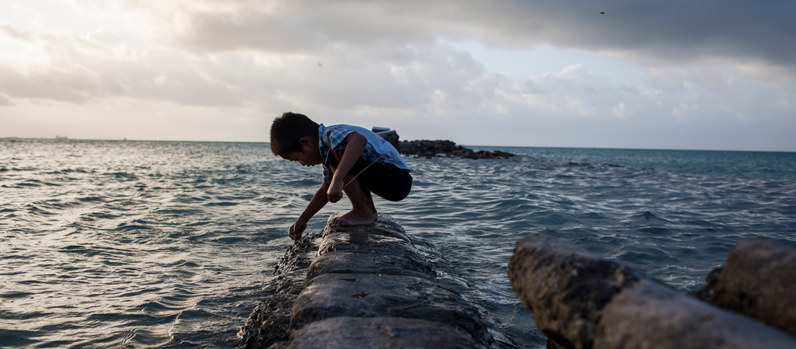 A boy plays on a flooded sea wall in Bikenibeu village, South Tarawa island of Kiribati.