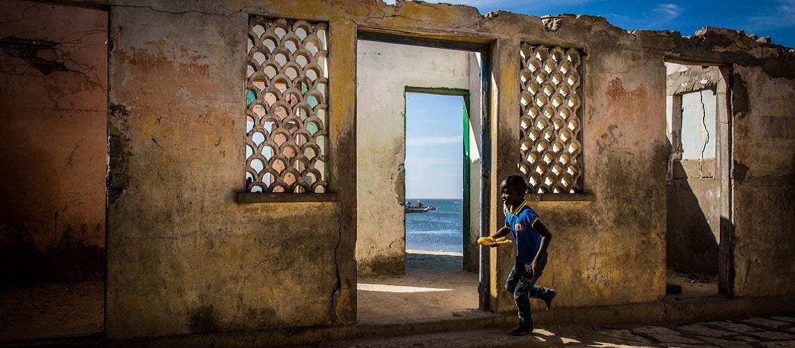 A girl runs by a house that is being destroyed by rising waters in Bargny, Senegal. A girl runs by a house that is being destroyed by rising waters in Bargny, Senegal.