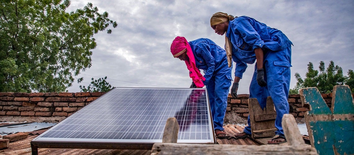 Women install solar panel on roof.