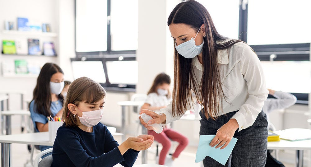 A teacher interacts with her students during COVID-19 times. / Shutterstock