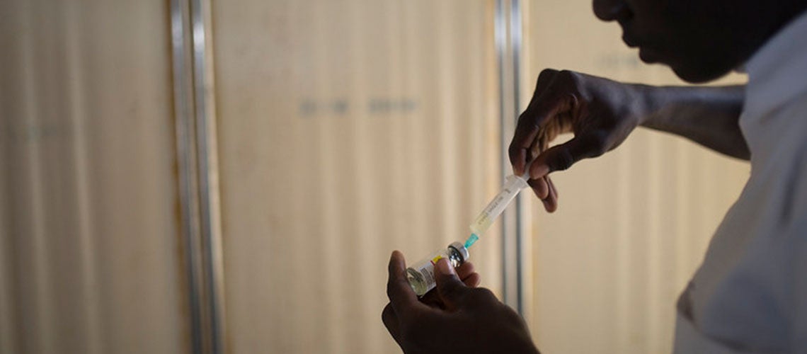 A man fills a syringe from a vial, Nigeria