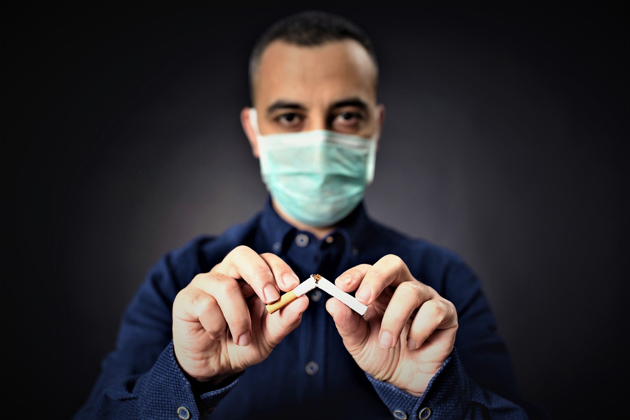 Man With Protective Face Mask Breaking Cigarette Man With Protective Face Mask Breaking Cigarette