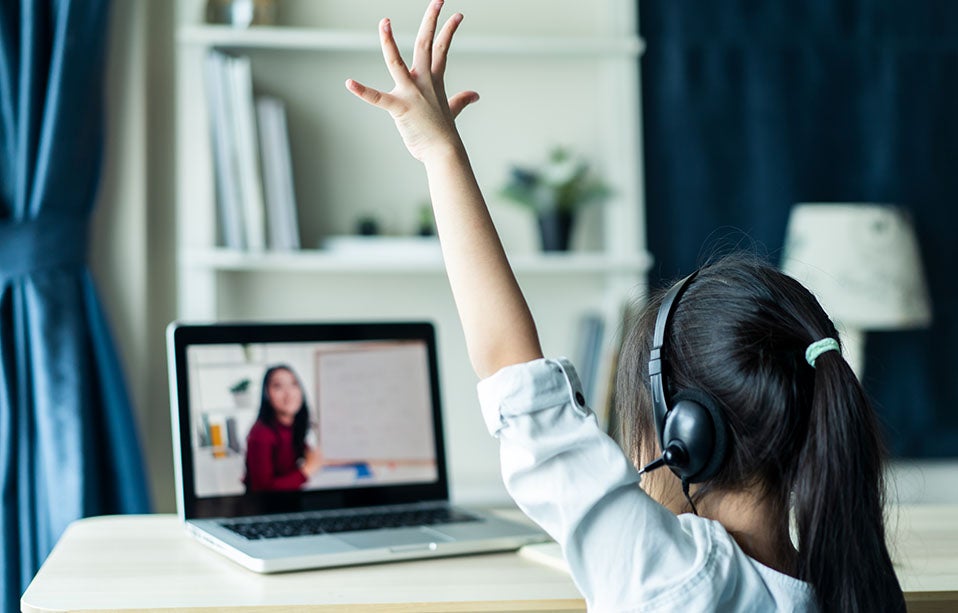 Young girl raises her hand during remote learning session.
