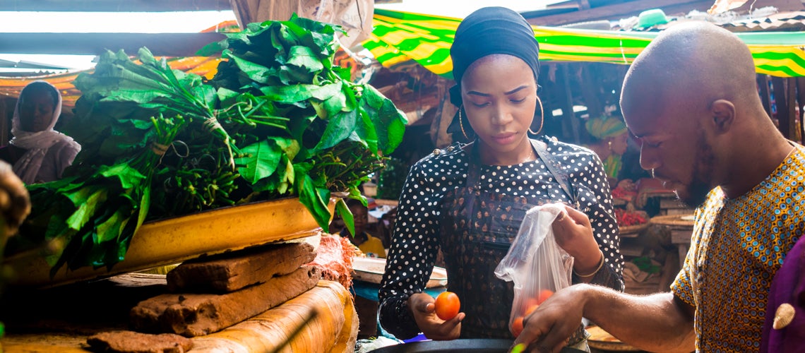A woman sells goods in an African market. Photo credit: Shutterstock