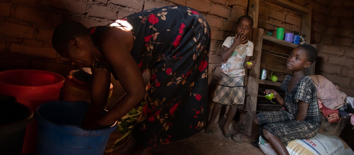 Mother with two beautiful daughters are working inside their house at a rural village in Malawi