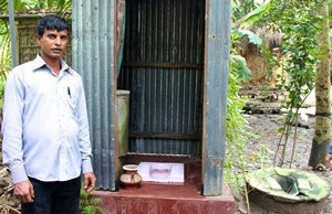Mr Jalal with one of the hygienic latrines he built for a family. To the right is the family?s old latrine.