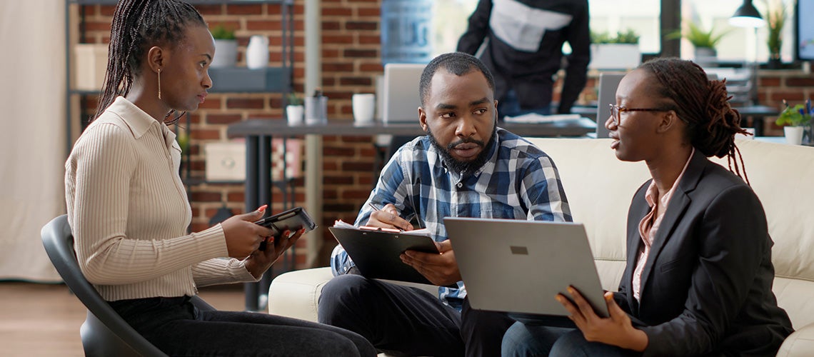 Office colleagues with their tablet and laptop in a meeting.