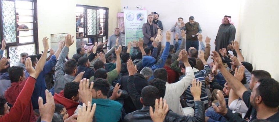 Community members raise their hands at a gathering. Community members raise their hands at a gathering.