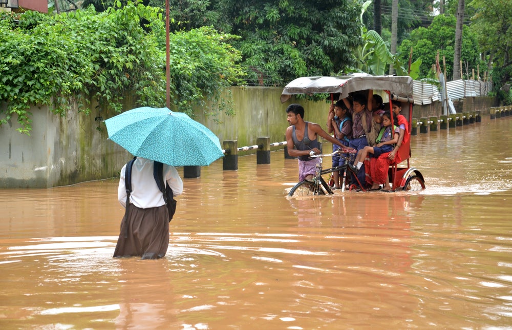 Local residents in an Indian town wade through floods after rains