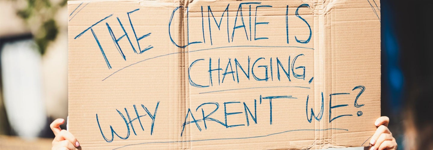 A protester holding a sign that reads "The climate is changing. Why aren't we?"