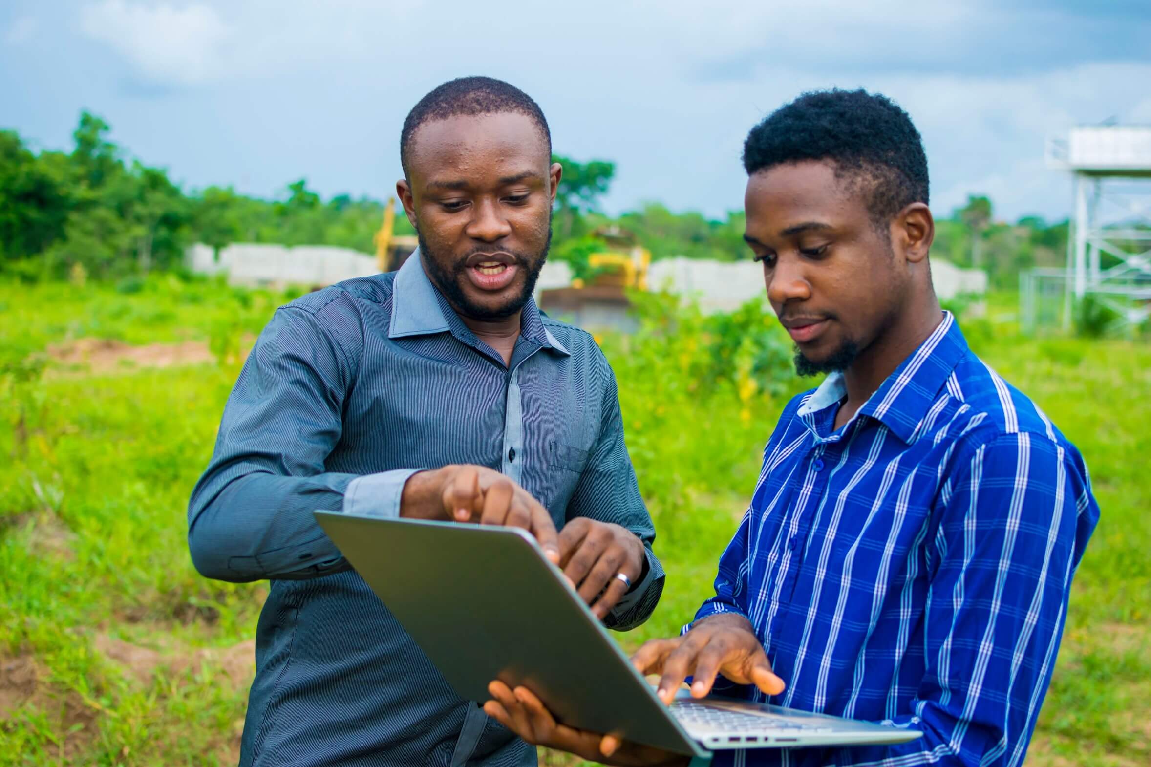 Young Cameroonian men standing on a farmland and reading a business plan to be executed on the farmland