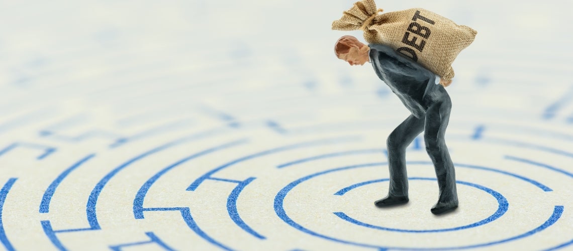 a plastic figure carrying a bag labeled 'debt' on top of a two-dimensional maze a plastic figure carrying a bag labeled 'debt' on top of a two-dimensional maze