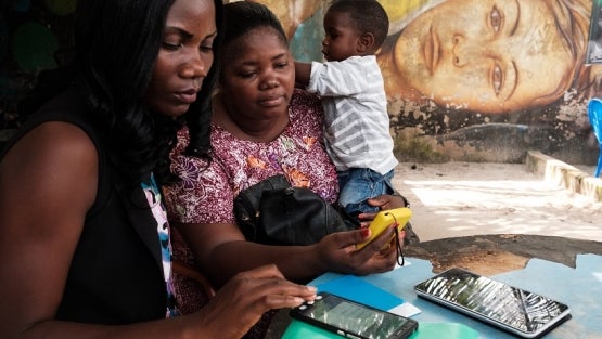  Two women use a mobile money payment device in Abidjan, Côte d?Ivoire. Photo: © Nyani Quarmyne/International Finance Corporation