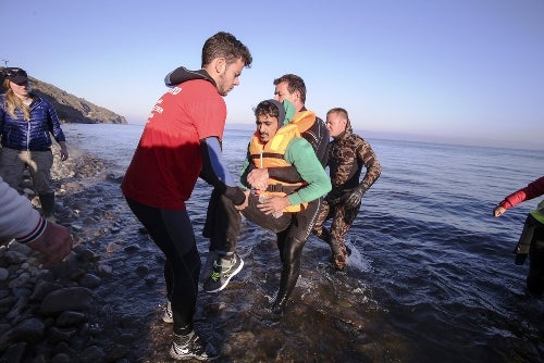 Volunteers carry disabled refugee - Nicolas Economou | Shutterstock.com