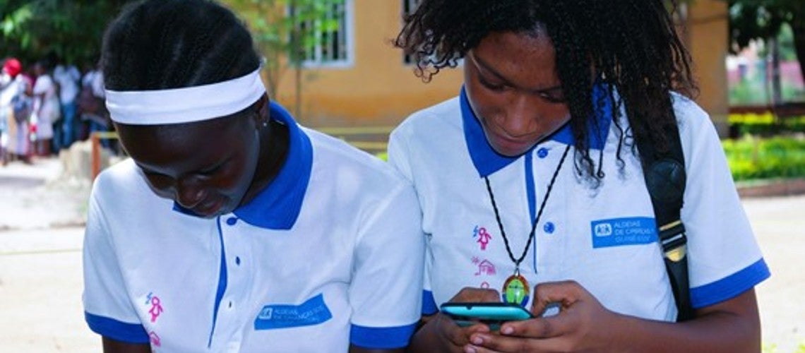 Two female grade school children in Bissau Guinea Bissau use their cellphones to check their homework after school