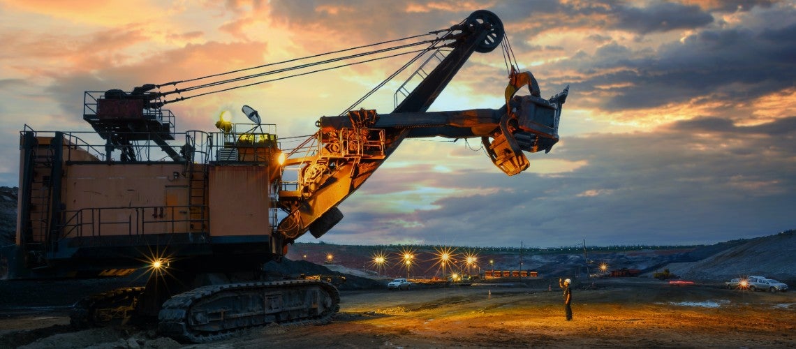 A construction worker stands in front of of an excavator in a construction site for renewable energy