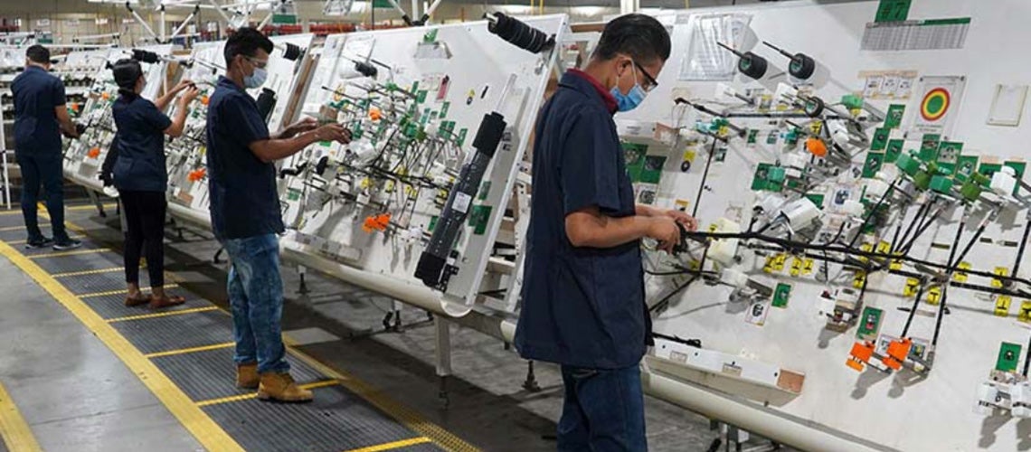 Workers wearing face masks operate standing appliances in a factory Workers wearing face masks operate standing appliances in a factory