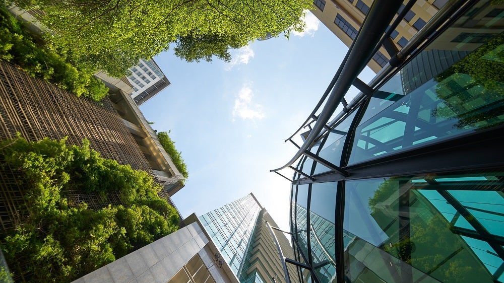Low angle shot of modern glass buildings and green with clear sky background. Low angle shot of modern glass buildings and green with clear sky background.