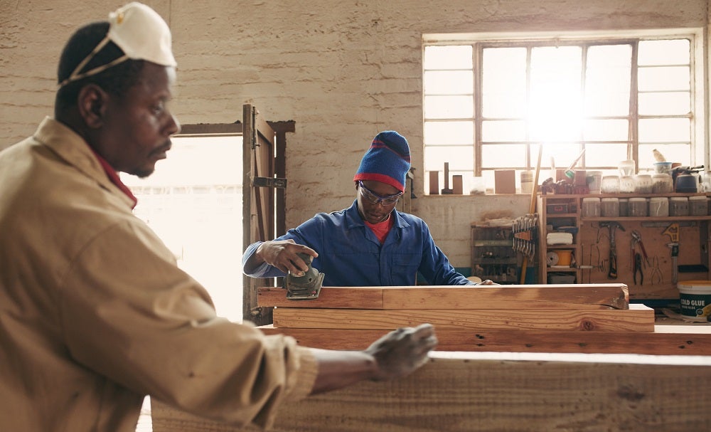 Two carpenters sanding planks 