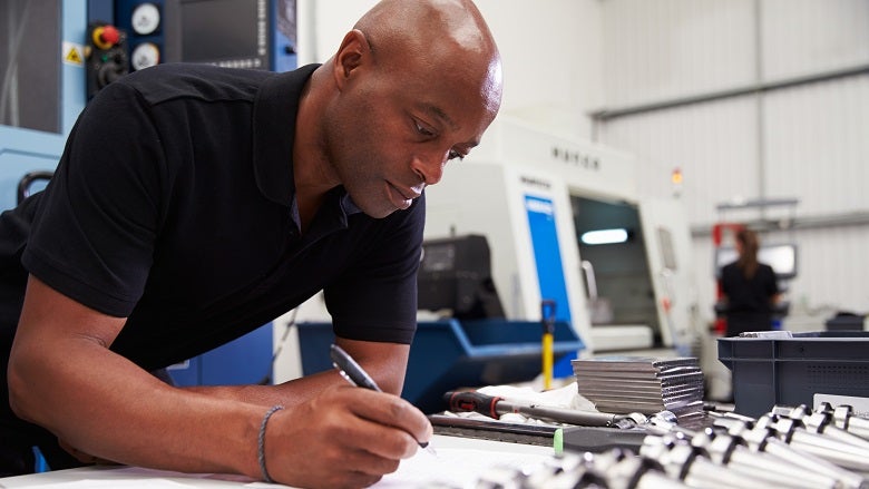 Engineer Planning Project With CNC Machinery In Background