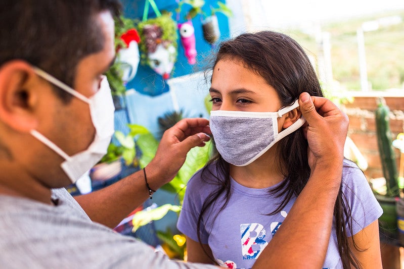 padre colocando cubre bocas a su hija