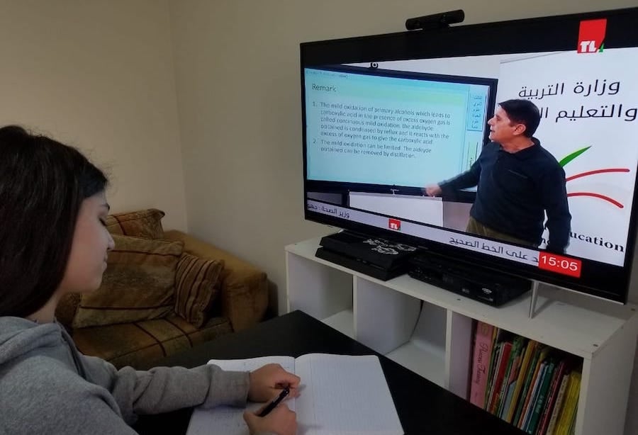 A young girl takes notes during her online instruction in Lebanon.