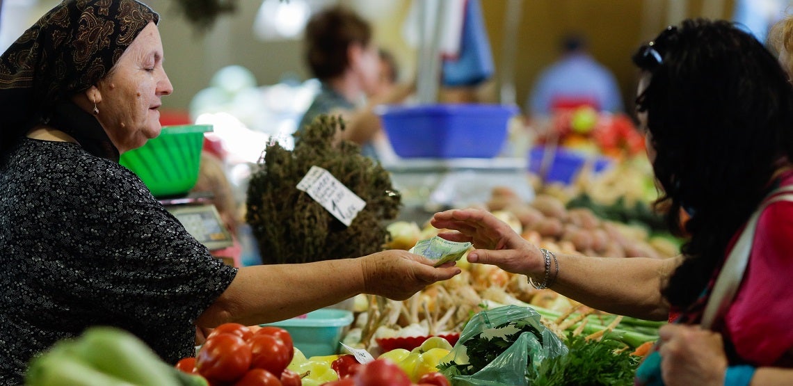 a woman buying vegetables from a stand in Obor market in Bucharest, Romania. a woman buying vegetables from a stand in Obor market in Bucharest, Romania.