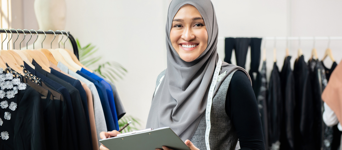 Une jeune femme travaillant dans un magasin de vêtements souriant à la camér- Credit: Atstock Productions/Shutterstock