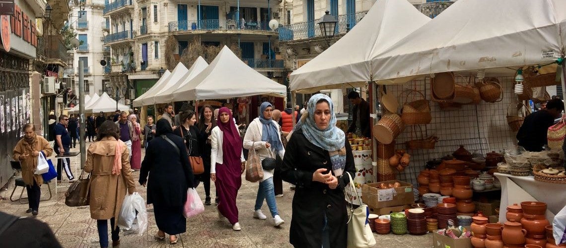 Shoppers walk through a market in Algeria.