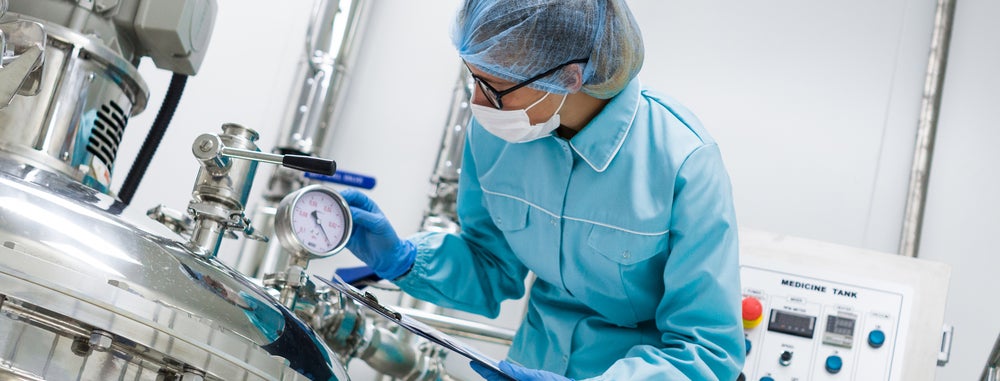 Woman working with large vat in lab. Woman working with large vat in lab.