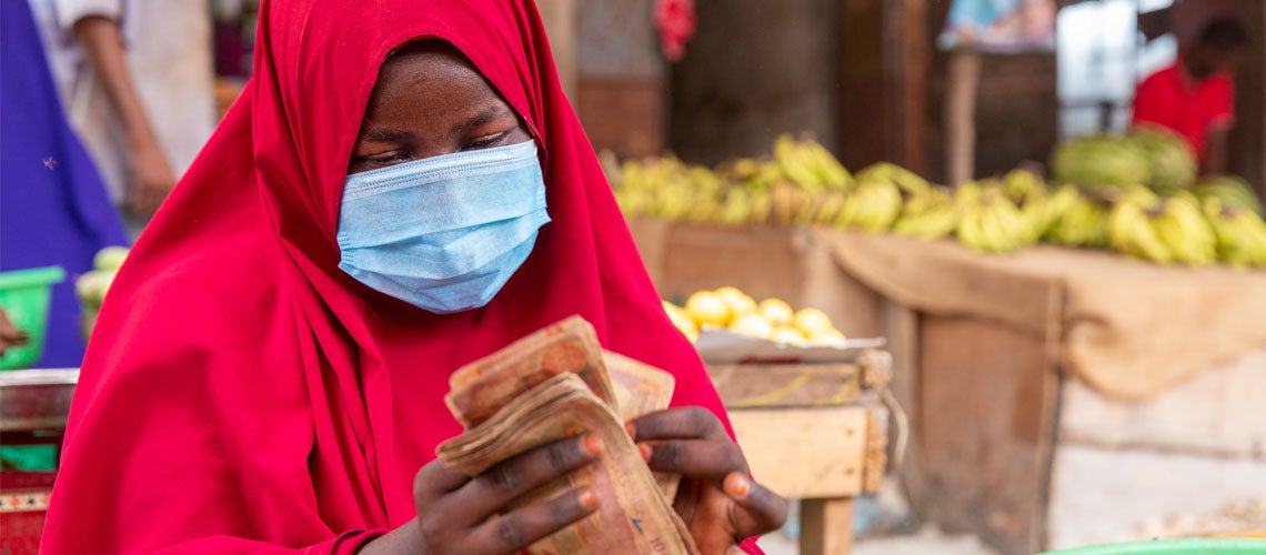 Somalia business woman counterchecks her earnings at the end of a busy market day. Photo: Mohamed Abdihakim, World Bank