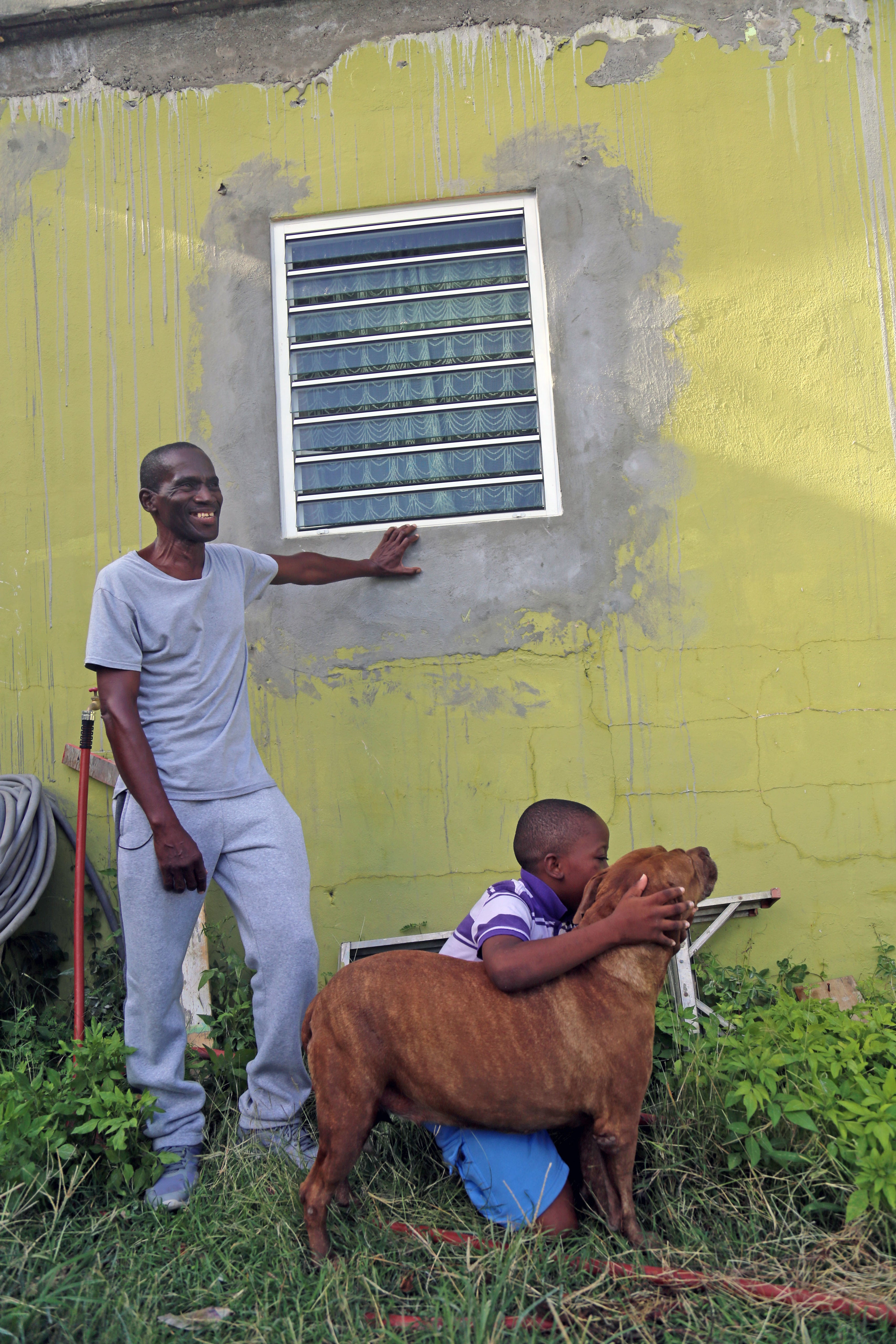 Project beneficiaries in front of their repaired home featuring new hurricane shutters