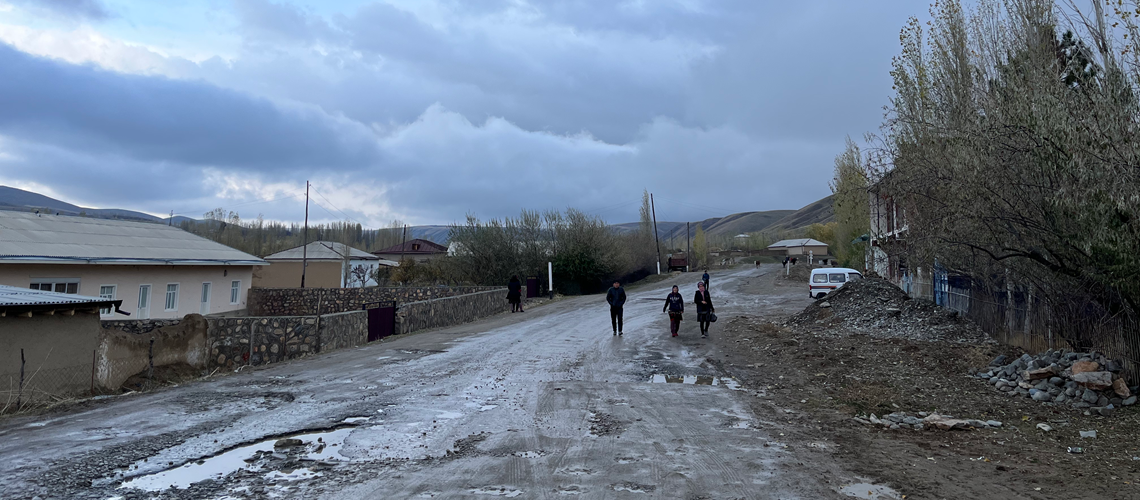 People walking in a muddy road in a village in Jizzakh Province, Uzbekistan.